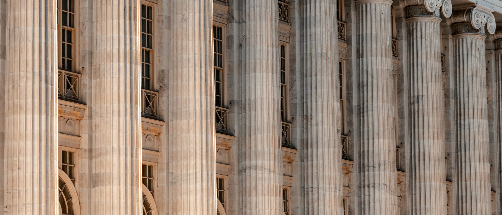 Long couloir d'un tribunal baigné de la lumière du matin, colonnes et sol de pierre, sans personnage.