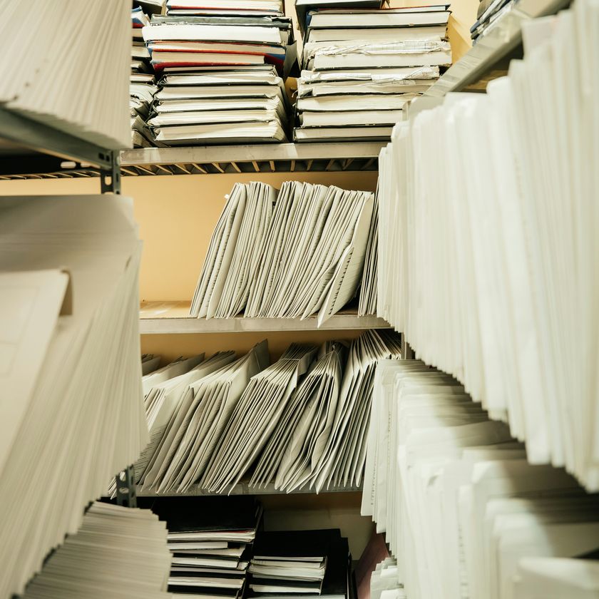 Gros plan sur des dossiers et pièces de procédure reliés et étiquetés, prêts à être ressaisis pour la facturation.