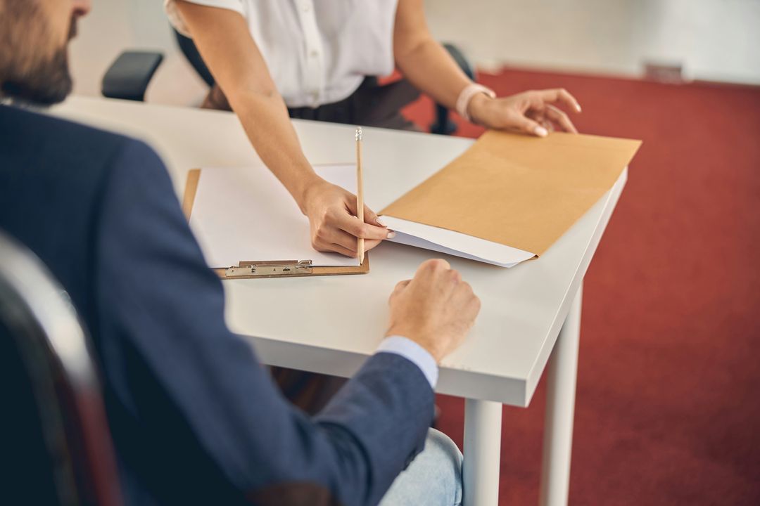 Un expert de justice examine attentivement une pièce du dossier à la loupe, sous une lumière de bureau.