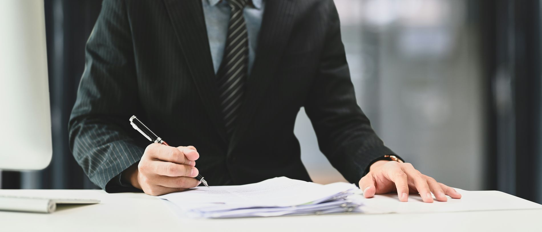 Un professionnel du judiciaire, en fin de journée, face à une pile de dossiers de procédure encore à traiter.